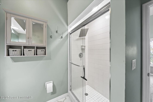 full bathroom with a shower stall and baseboards