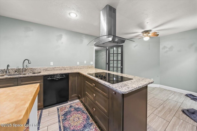 kitchen featuring a peninsula, light stone countertops, island exhaust hood, black appliances, and a sink