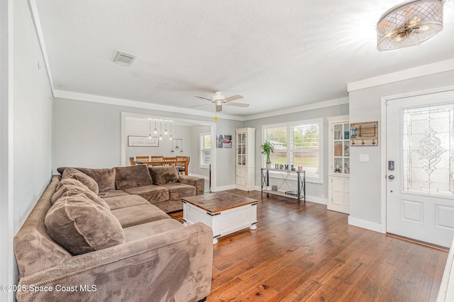 living area featuring dark wood-style floors, visible vents, crown molding, and a textured ceiling