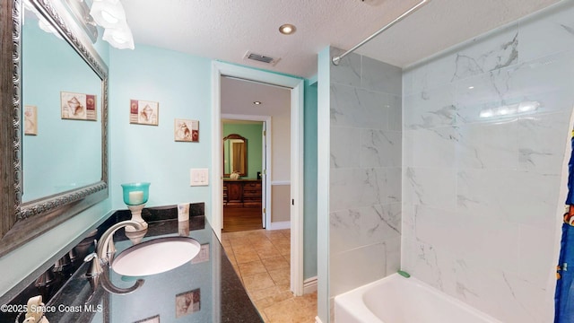 full bath with a textured ceiling, tile patterned flooring, bathing tub / shower combination, vanity, and visible vents