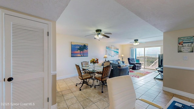 dining space featuring light tile patterned floors, ceiling fan, baseboards, and a textured ceiling