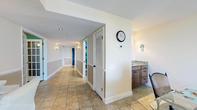 hallway with recessed lighting, baseboards, and light tile patterned floors