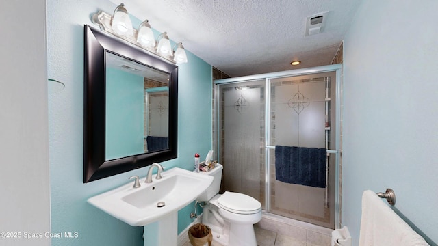 full bath featuring a stall shower, visible vents, toilet, a textured ceiling, and a sink