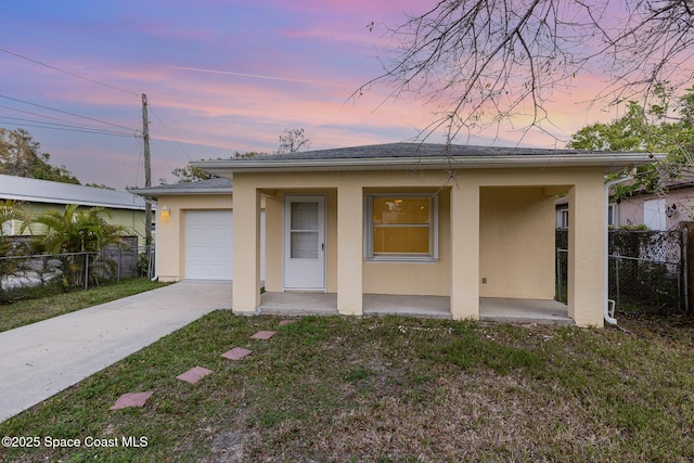 view of front facade with a garage, fence, driveway, a yard, and stucco siding