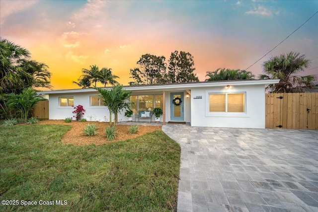 single story home featuring a lawn, fence, and stucco siding