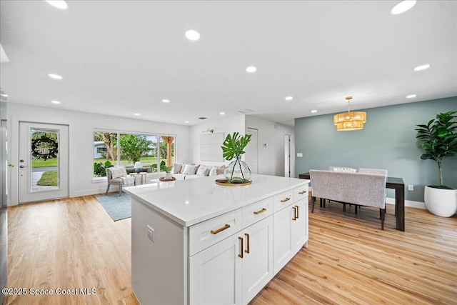 kitchen featuring white cabinets, open floor plan, decorative light fixtures, light countertops, and light wood-style floors