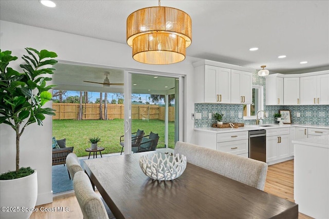 kitchen featuring pendant lighting, light countertops, backsplash, white cabinetry, and a sink