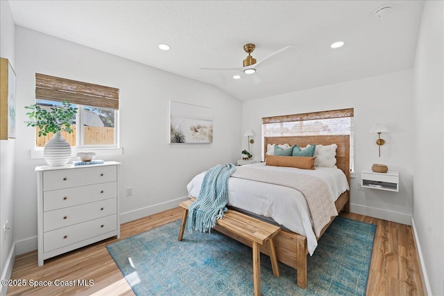 bedroom with lofted ceiling, light wood finished floors, baseboards, and recessed lighting