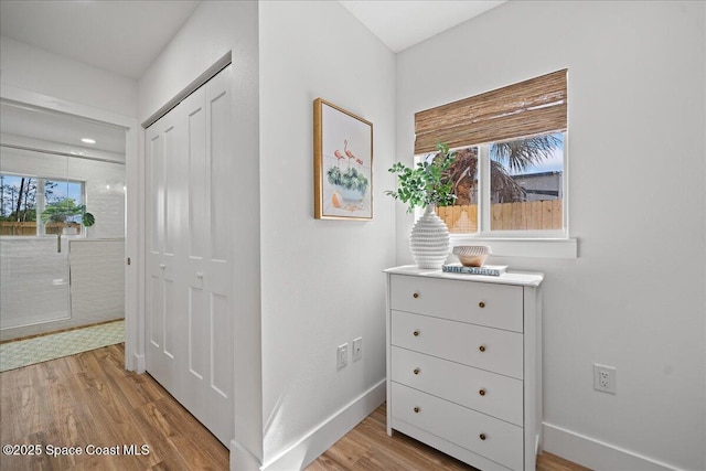 hallway with light wood-style flooring and baseboards