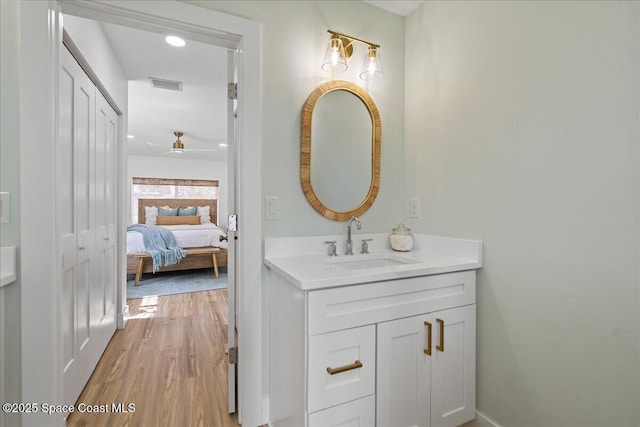 bathroom featuring ensuite bathroom, wood finished floors, vanity, visible vents, and a closet