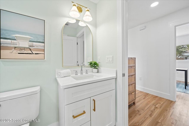 bathroom featuring toilet, recessed lighting, wood finished floors, vanity, and baseboards