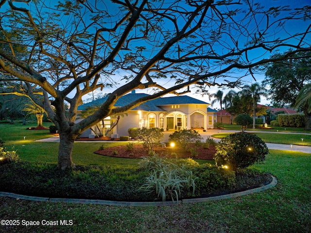 view of front of house featuring a yard, driveway, and stucco siding