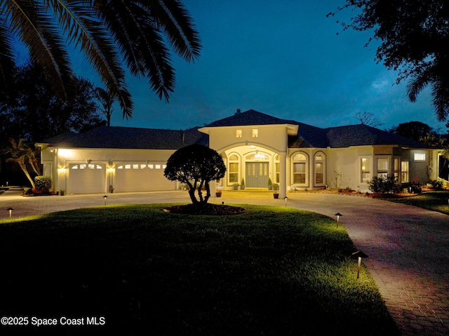 mediterranean / spanish house featuring curved driveway, a lawn, and stucco siding