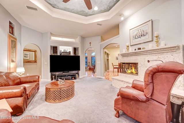 living room with arched walkways, carpet, a raised ceiling, and visible vents