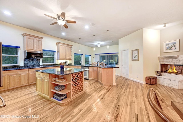 kitchen featuring light brown cabinetry, stainless steel appliances, pendant lighting, and a center island