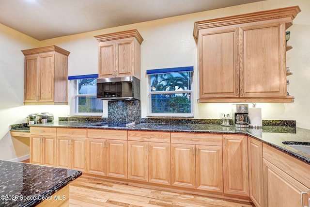 kitchen featuring light wood-style floors, stovetop, dark stone countertops, and light brown cabinetry