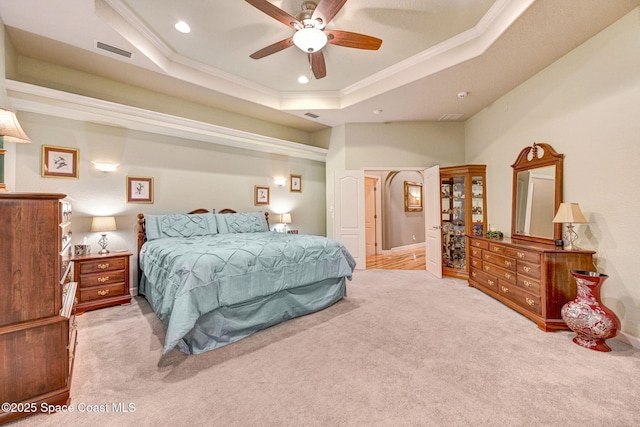 bedroom with ornamental molding, a tray ceiling, visible vents, and light carpet