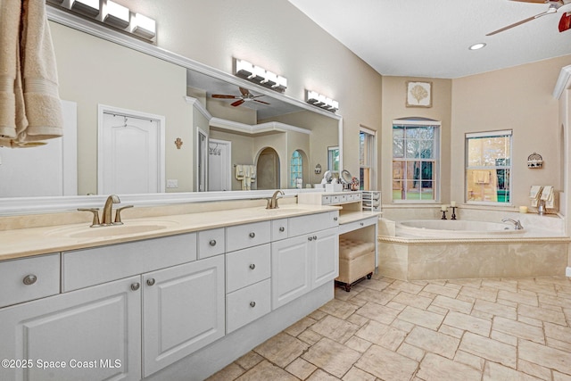 bathroom featuring double vanity, a garden tub, a ceiling fan, and a sink