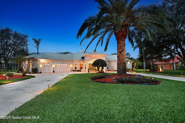 single story home featuring an attached garage, driveway, a front yard, and stucco siding