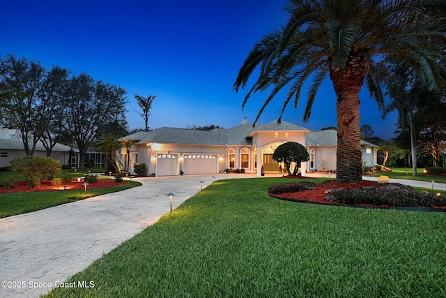 view of front of property with a front yard, driveway, an attached garage, and stucco siding