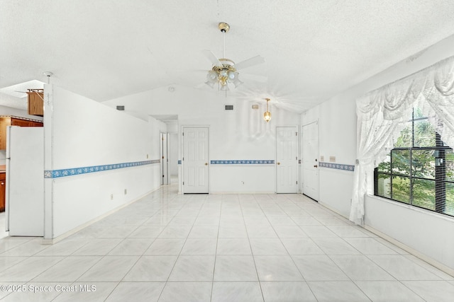 tiled spare room with a textured ceiling, lofted ceiling, and ceiling fan