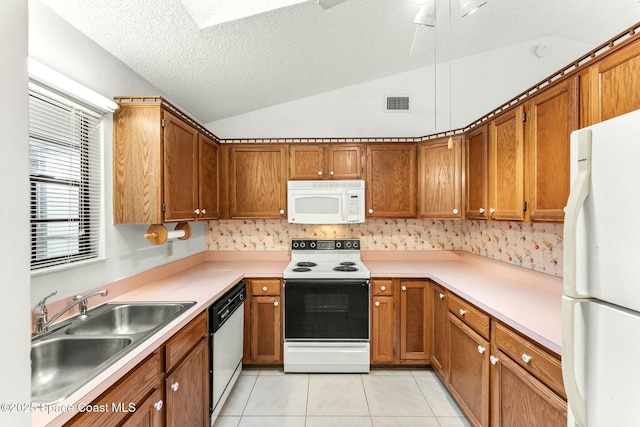 kitchen featuring white appliances, vaulted ceiling, sink, light tile patterned floors, and a textured ceiling