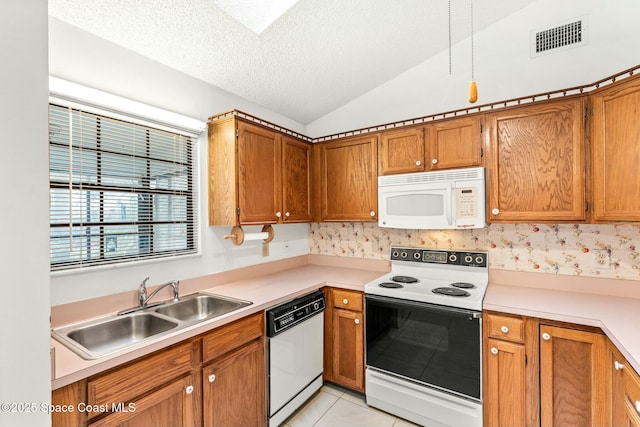 kitchen with white appliances, lofted ceiling, sink, light tile patterned floors, and a textured ceiling