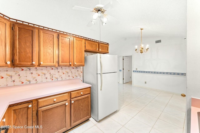 kitchen featuring hanging light fixtures, light tile patterned flooring, vaulted ceiling, ceiling fan with notable chandelier, and white fridge