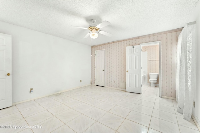 unfurnished bedroom with ensuite bathroom, light tile patterned floors, ceiling fan, and a textured ceiling