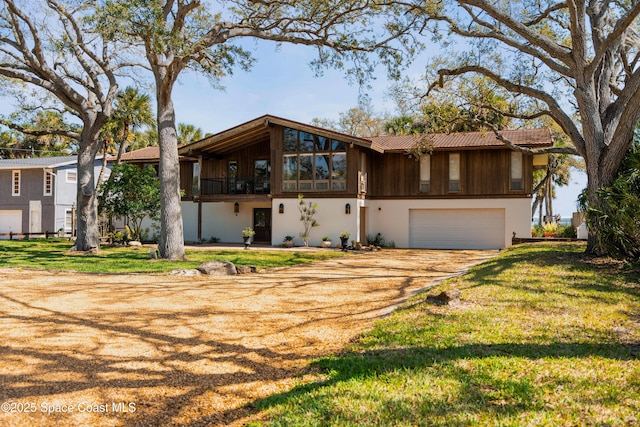 view of front of house with a garage, a front yard, and dirt driveway