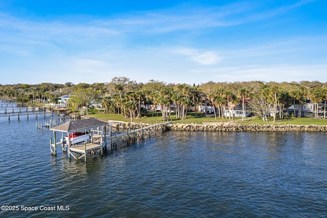 dock area featuring a water view, boat lift, and a yard