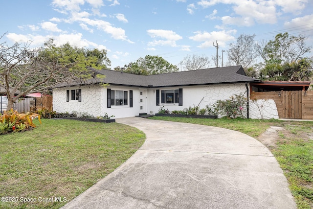 single story home with stone siding, a front yard, driveway, roof with shingles, and fence