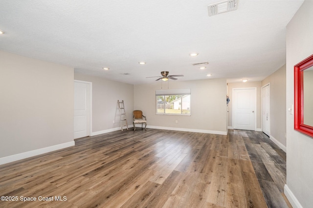 interior space with baseboards, visible vents, a ceiling fan, and wood finished floors