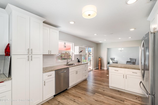 kitchen featuring light stone counters, white cabinetry, a sink, and appliances with stainless steel finishes