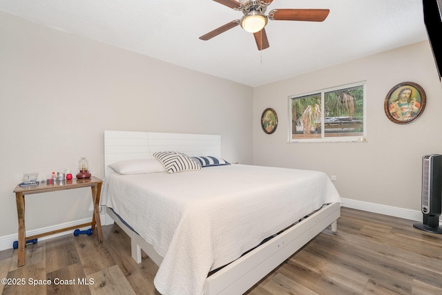 bedroom with a ceiling fan, baseboards, and wood finished floors