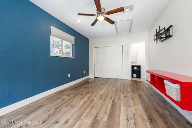 unfurnished bedroom with light wood-style flooring, visible vents, baseboards, attic access, and a closet