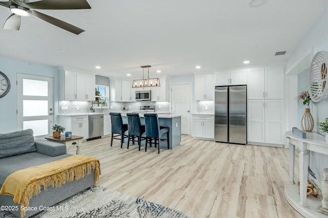 kitchen with light countertops, appliances with stainless steel finishes, decorative light fixtures, and white cabinets