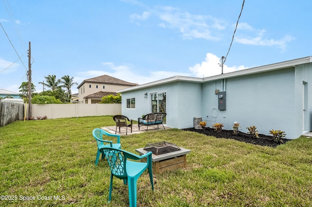 rear view of property with stucco siding, a fenced backyard, a fire pit, and a yard