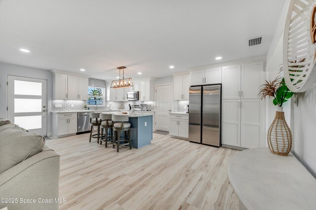 122 Poinsetta St, Indialantic, FL 32903 - kitchen with appliances with stainless steel finishes, open floor plan, a breakfast bar, tasteful backsplash, and recessed lighting