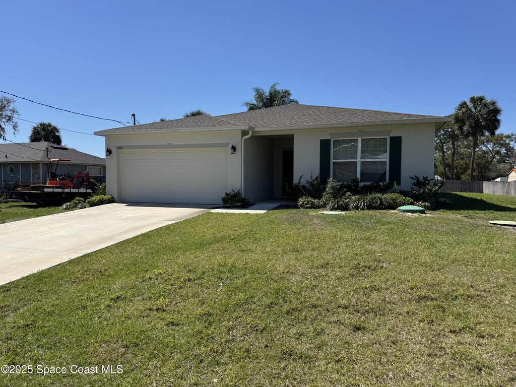 ranch-style home featuring a garage, driveway, a front lawn, and stucco siding