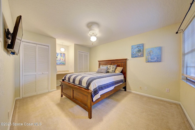 bedroom featuring light colored carpet, a textured ceiling, and baseboards