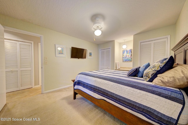 bedroom featuring light carpet, baseboards, and multiple closets