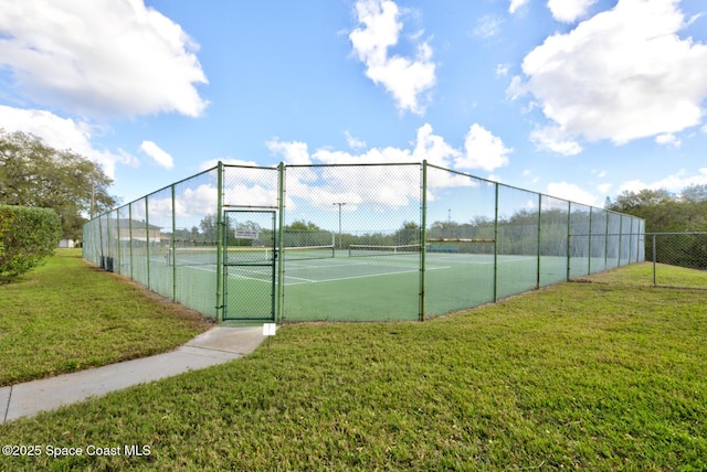 view of tennis court with a gate, fence, and a yard