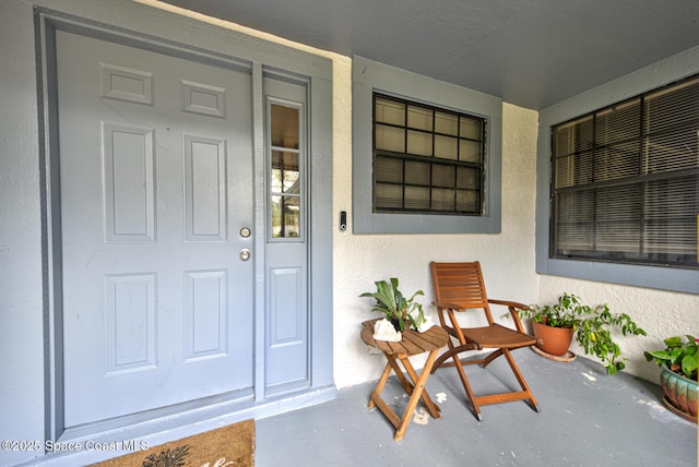 view of exterior entry featuring a porch and stucco siding