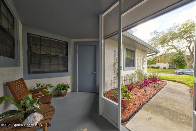 entrance to property featuring covered porch and stucco siding