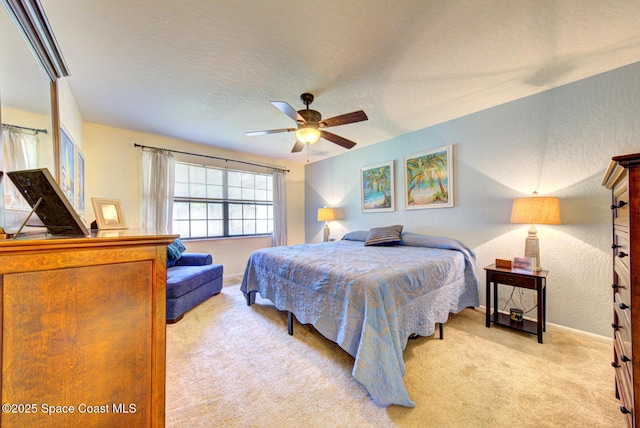 bedroom featuring a textured ceiling, a textured wall, ceiling fan, light carpet, and baseboards