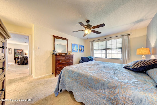 bedroom with light colored carpet, ceiling fan, and a textured ceiling