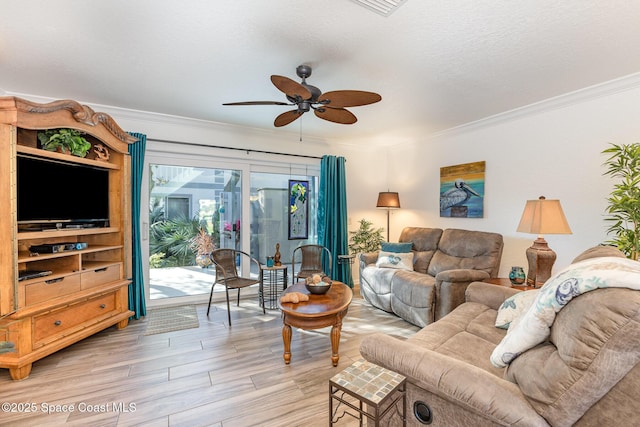 living room featuring light wood finished floors, ceiling fan, ornamental molding, and a textured ceiling