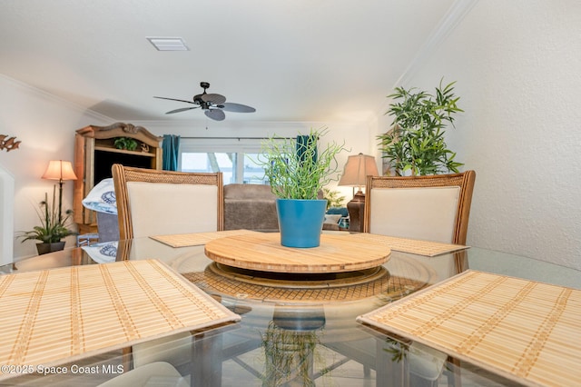 dining room with a ceiling fan, crown molding, and a textured wall