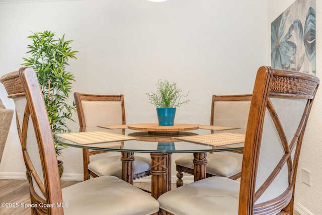 dining room with a textured wall, wood finished floors, and baseboards